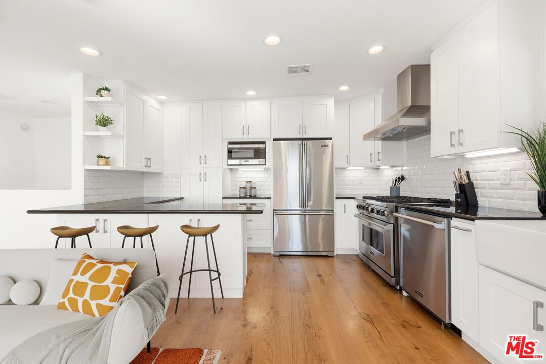 1788 North Orange Grove Avenue Los Angeles, CA 90046 - Photo 5 of 20 a kitchen with stainless steel appliances granite countertop a sink a stove a refrigerator and island with wooden floor