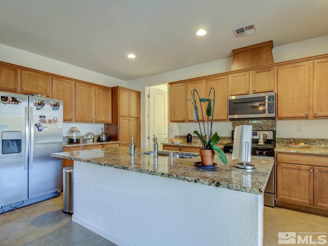 9885 Shadowless Trail Reno, NV 89521 - Photo 4 of 25 a kitchen with stainless steel appliances granite countertop a refrigerator a stove top oven a sink a dining table and chairs