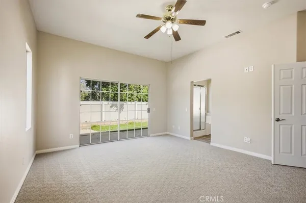an empty room with chandelier fan and windows