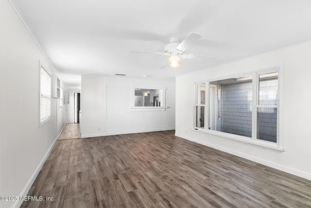 a view of an empty room with a window and wooden floor