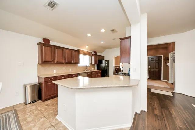a large kitchen with stainless steel appliances granite countertop a sink a stove and a wooden floors