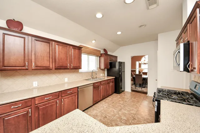 a large kitchen with stainless steel appliances granite countertop a refrigerator and stove