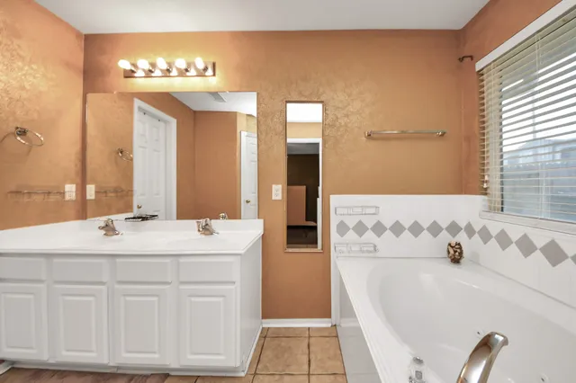 a spacious bathroom with double vanity and a mirror