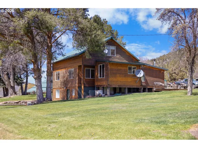 a view of a house with a big yard and large tree