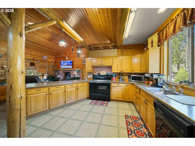 a kitchen with stainless steel appliances kitchen island granite countertop a sink counter space cabinets and a large window