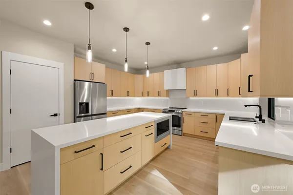 a large kitchen with kitchen island a sink stainless steel appliances and a large window