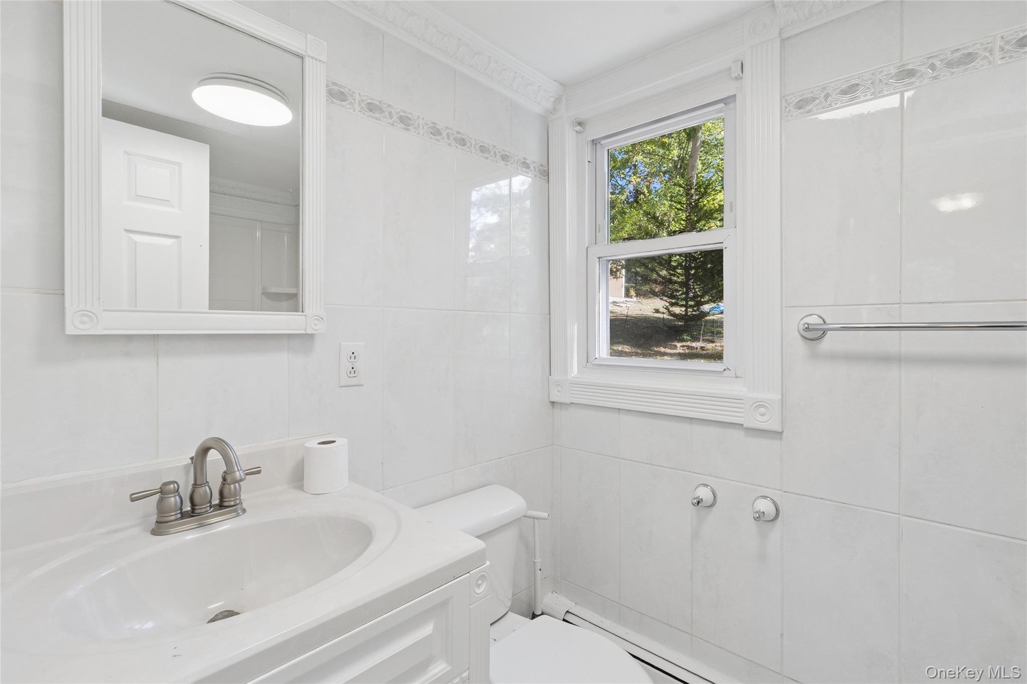 7 Yucca Road Rocky Point, NY 11778 - Photo 9 of 22 a bathroom with a toilet a sink a mirror a window and vanity