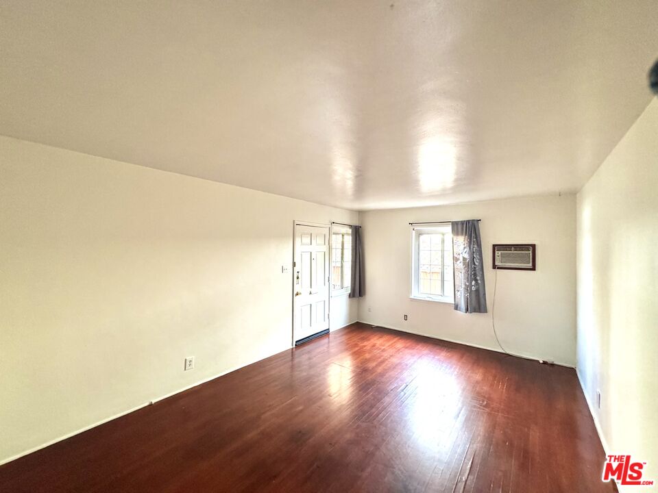 11928 Magnolia Boulevard, Unit 1/4 Valley Village, CA 91607 - Photo 2 of 9 a view of an empty room with wooden floor and a window