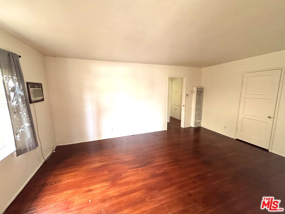 11928 Magnolia Boulevard, Unit 1/4 Valley Village, CA 91607 - Photo 3 of 9 a view of an empty room with wooden floor and a window
