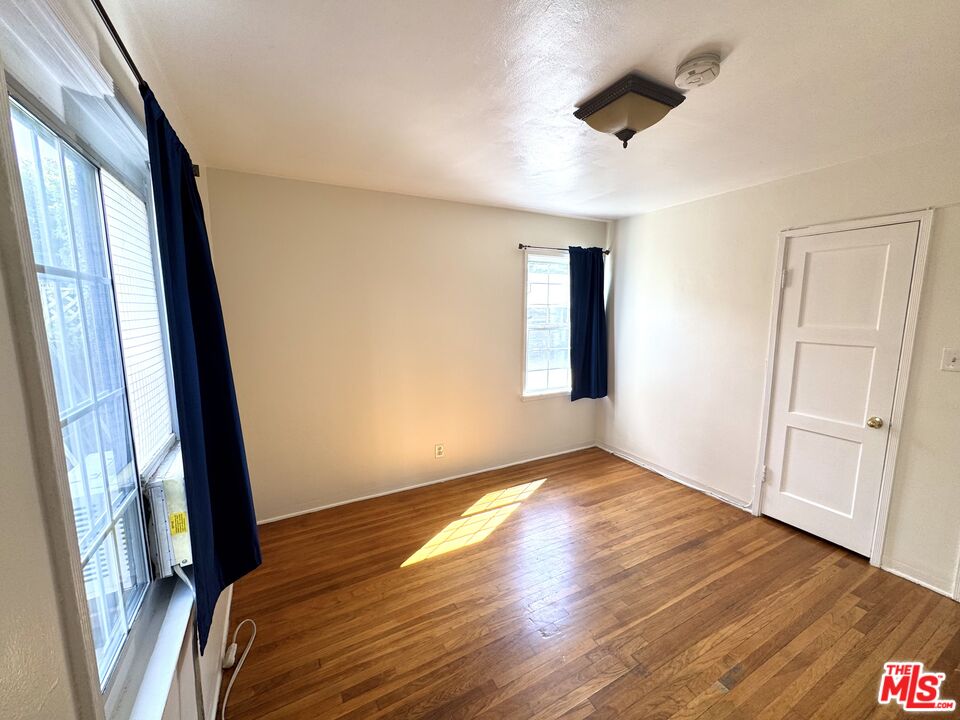 11928 Magnolia Boulevard, Unit 1/4 Valley Village, CA 91607 - Photo 4 of 9 a view of empty room with wooden floor and fan