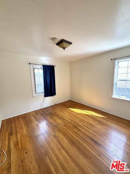 11928 Magnolia Boulevard, Unit 1/4 Valley Village, CA 91607 - Photo 5 of 9 an empty room with wooden floor and windows