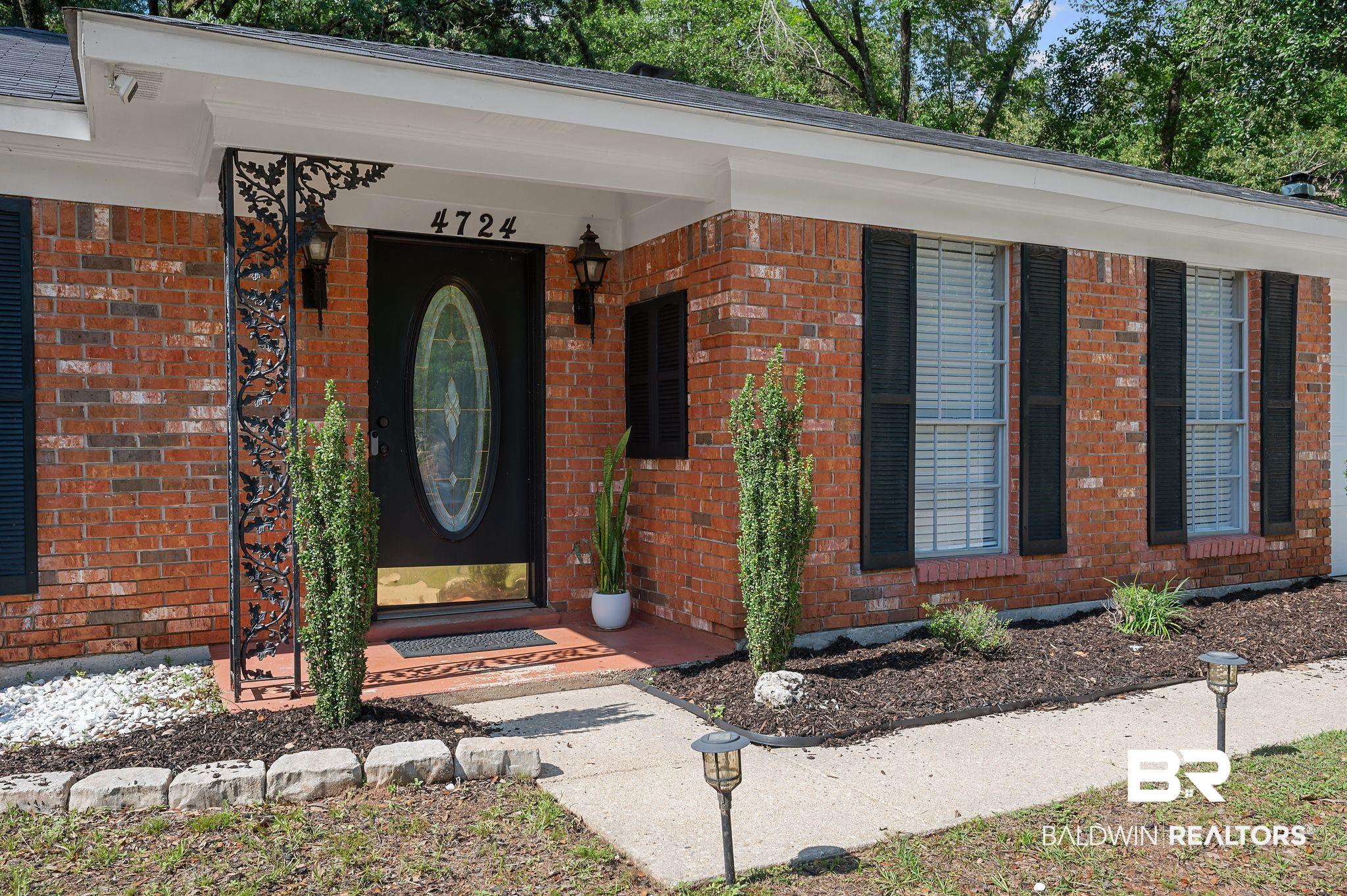 4724 Wicker Way Mobile, AL 36609 - Photo 3 of 36 Brick exterior with a covered entry featuring an ornate wrought iron pillar, a decorative oval-lite door, and two exterior sconces