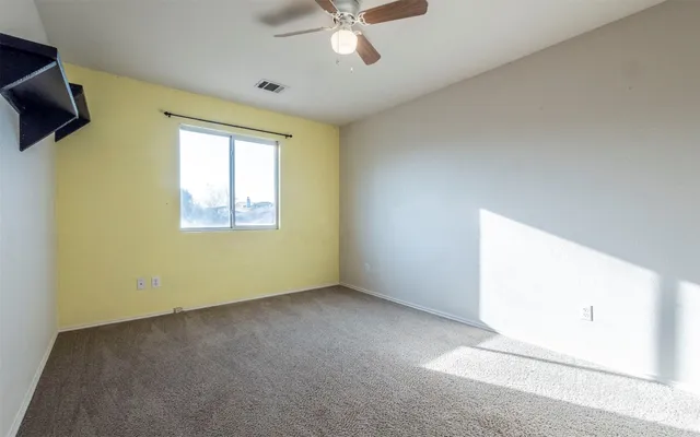 an empty room with windows and fan