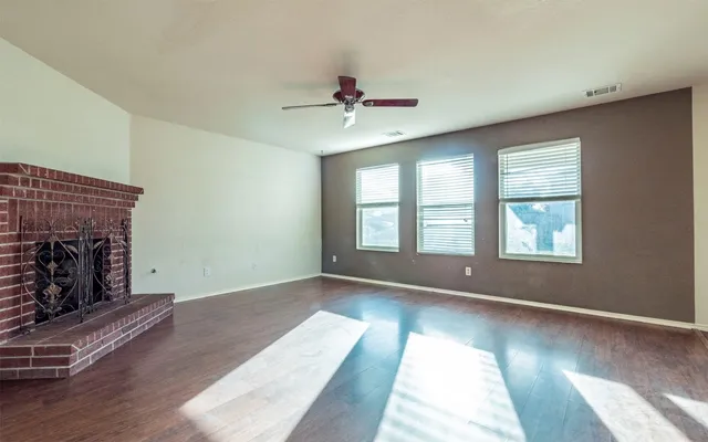 an empty room with windows and fireplace