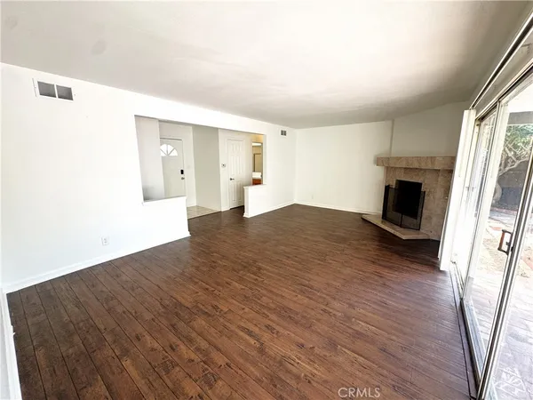 a view of empty room with wooden floor and fireplace