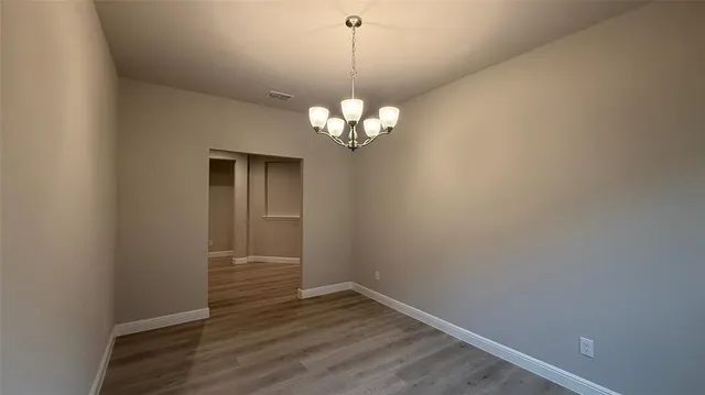 a view of a chandelier in big room with wooden floor