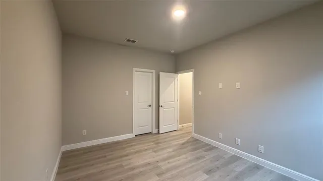a view of an empty room with wooden floor and closet