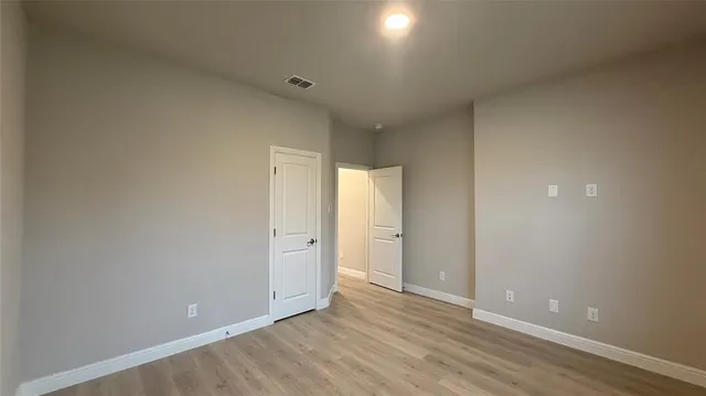a view of an empty room with wooden floor and closet