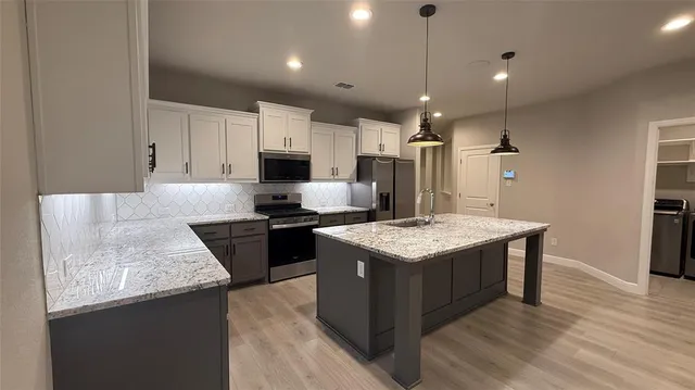 a kitchen with kitchen island a stove sink and refrigerator