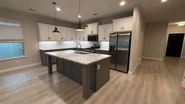 a kitchen with stainless steel appliances granite countertop a refrigerator a sink a stove a microwave and wooden floor