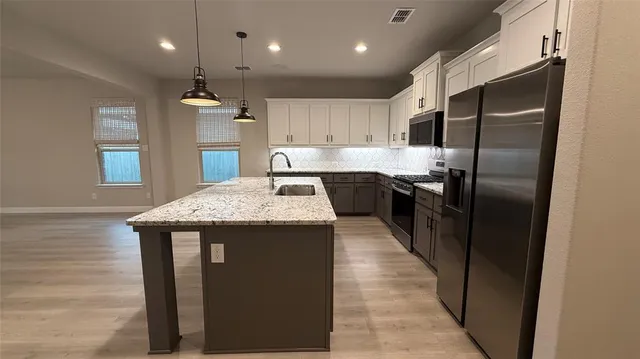 a kitchen with granite countertop kitchen island stainless steel appliances a sink stove and refrigerator