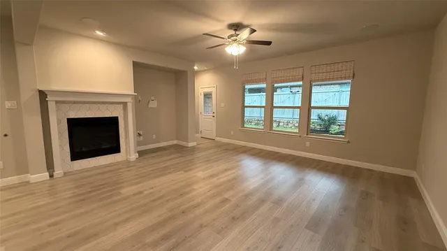 an empty room with windows fireplace and a kitchen view