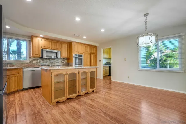 a kitchen with stainless steel appliances granite countertop a refrigerator oven a sink dishwasher and a refrigerator with wooden floor