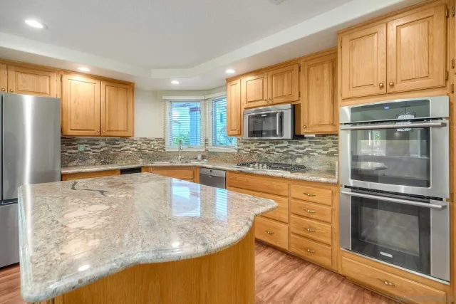 a kitchen with stainless steel appliances granite countertop a sink stove and refrigerator