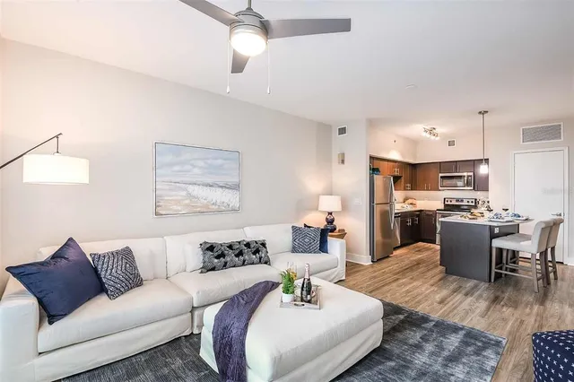 a living room with furniture kitchen view and a chandelier