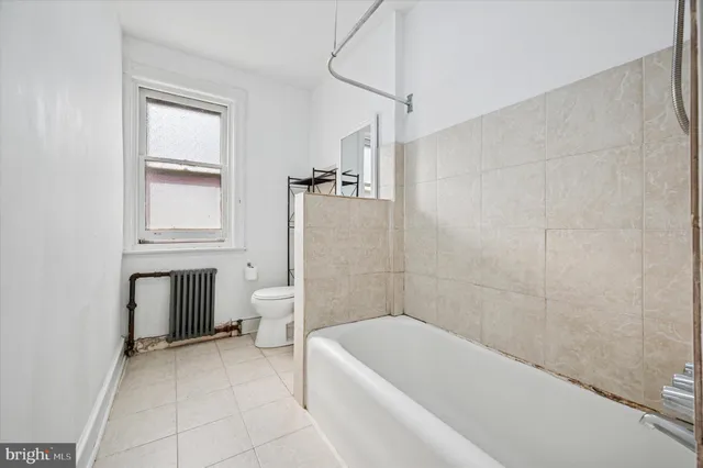 a bathroom with a tub a toilet and a window