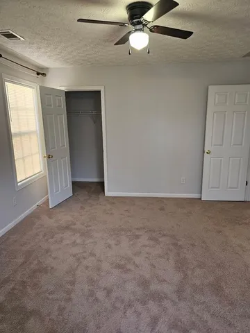an empty room with windows and fan