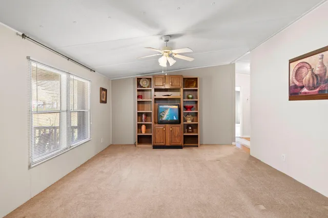 an empty room with windows and ceiling fan