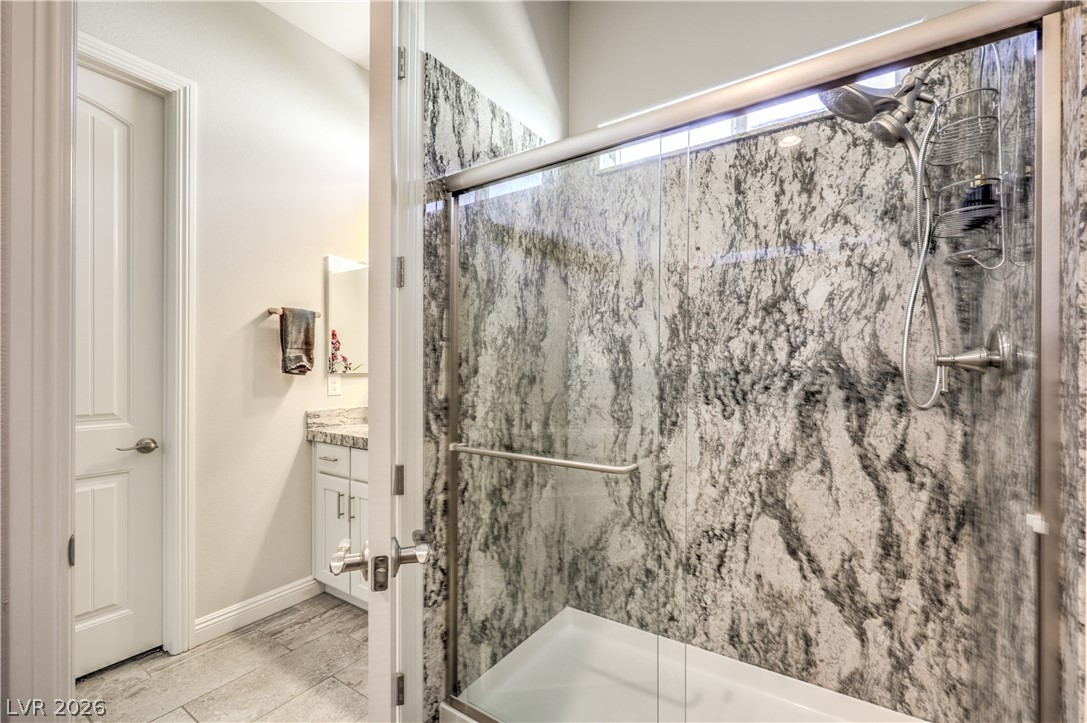 7119 Arabian Ridge Street Las Vegas, NV 89131 - Photo 38 of 73 A well-appointed bathroom features a spacious glass-enclosed shower with luxurious stone-patterned walls.