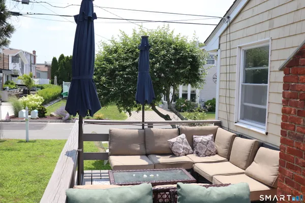 a view of a patio with couches plants and large trees