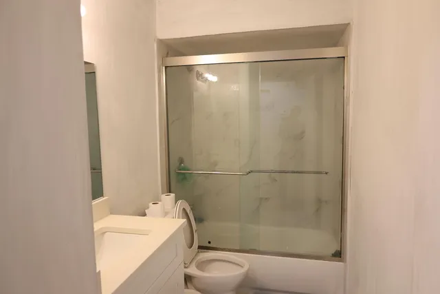 a bathroom with a granite countertop sink a toilet and shower