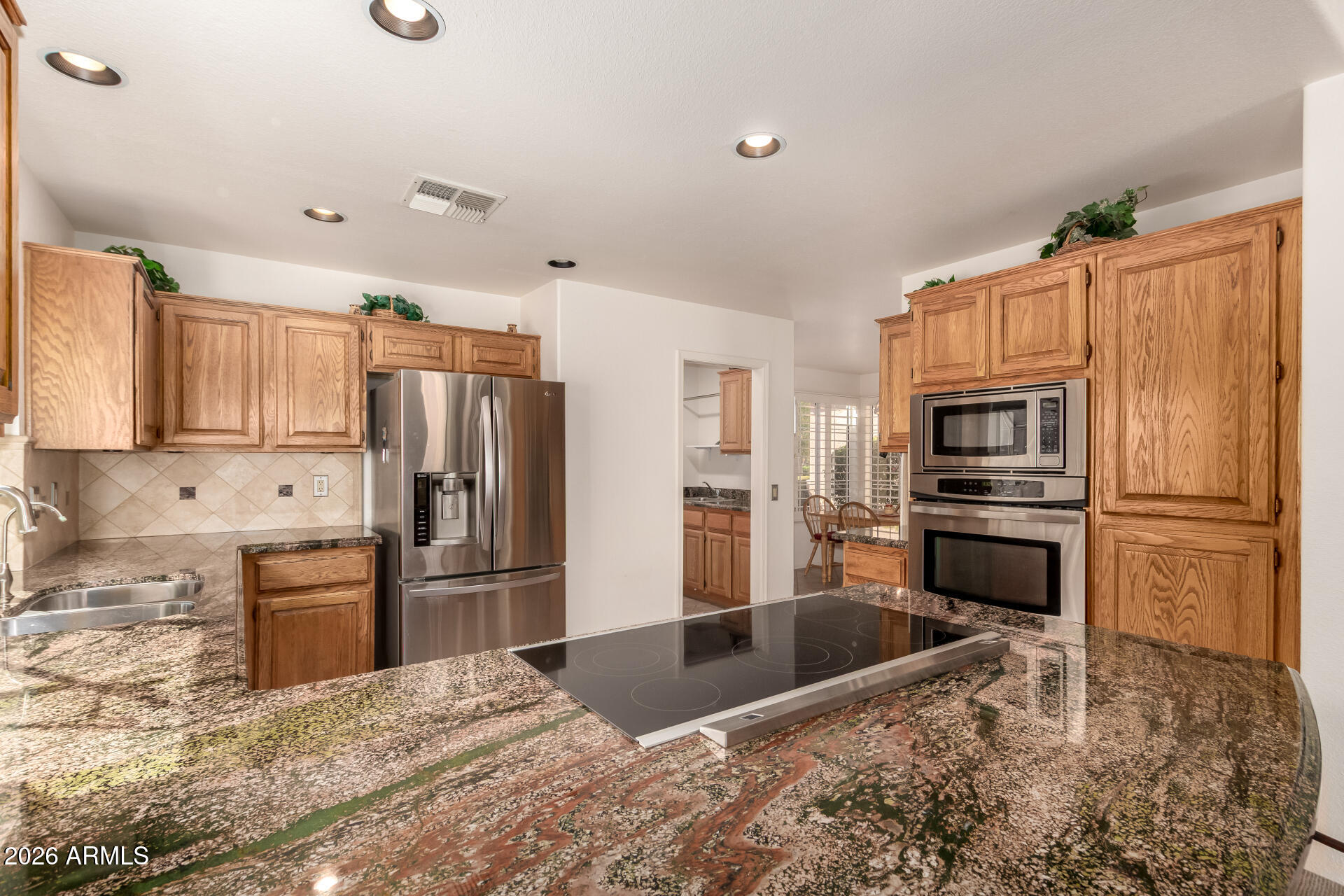 a kitchen with granite countertop a refrigerator and a stove top oven
