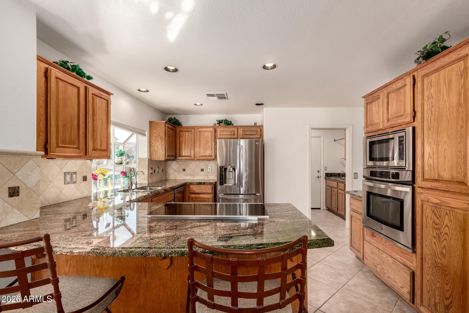 10904 East Spring Creek Road Sun Lakes, AZ 85248 - Photo 16 of 37 a kitchen with stainless steel appliances granite countertop a stove top oven a sink dishwasher a dining table and chairs with wooden floor