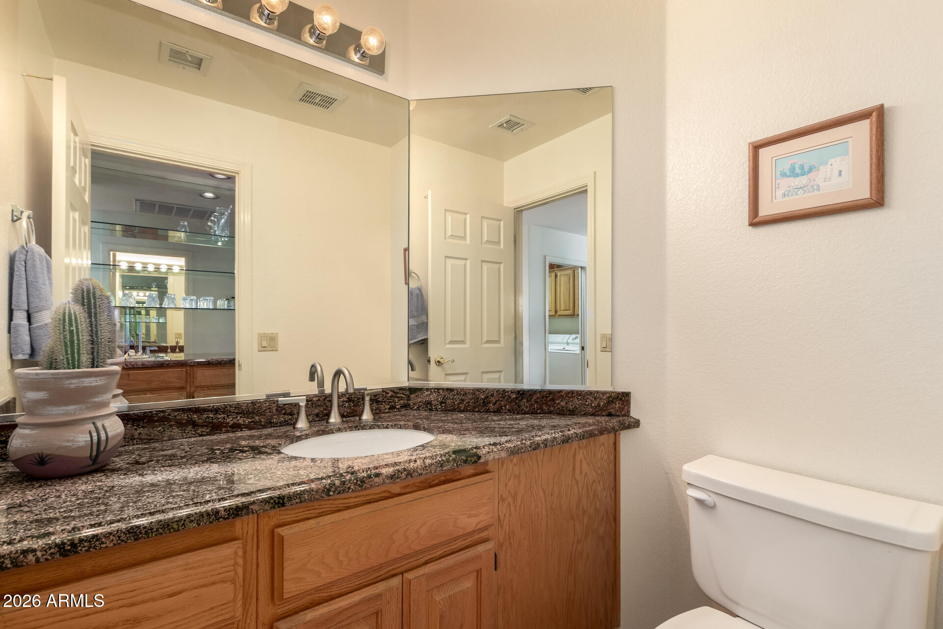 10904 East Spring Creek Road Sun Lakes, AZ 85248 - Photo 19 of 37 a bathroom with a granite countertop sink a large mirror and a toilet