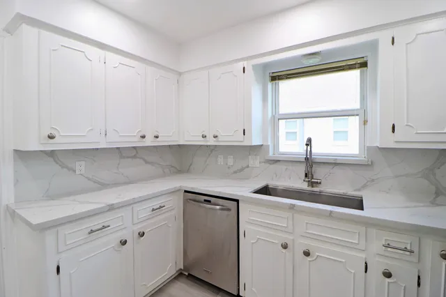 a kitchen with white cabinets and a window