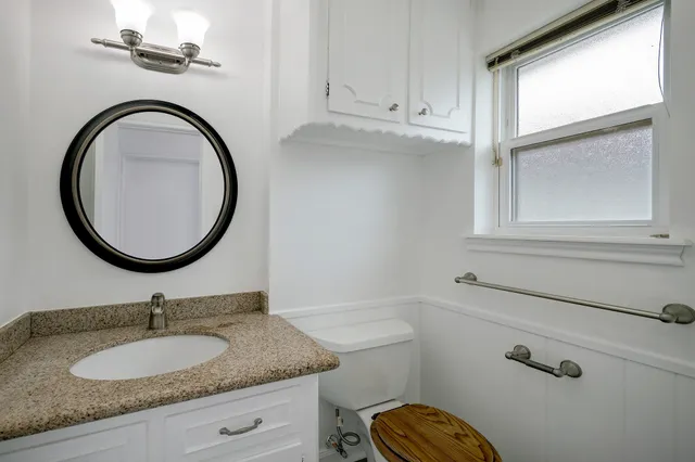 a bathroom with a granite countertop toilet a sink and a mirror