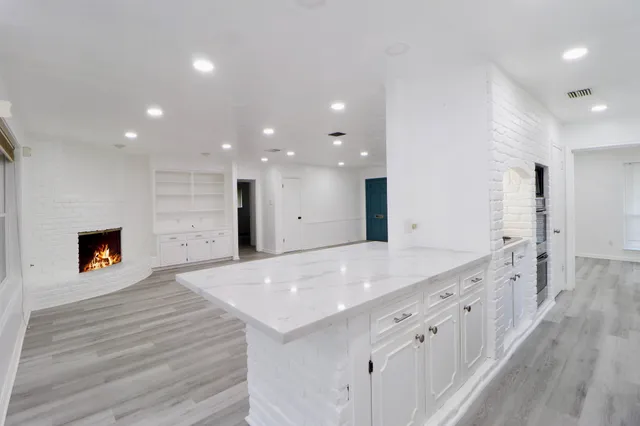 a large white kitchen with a sink and a fireplace