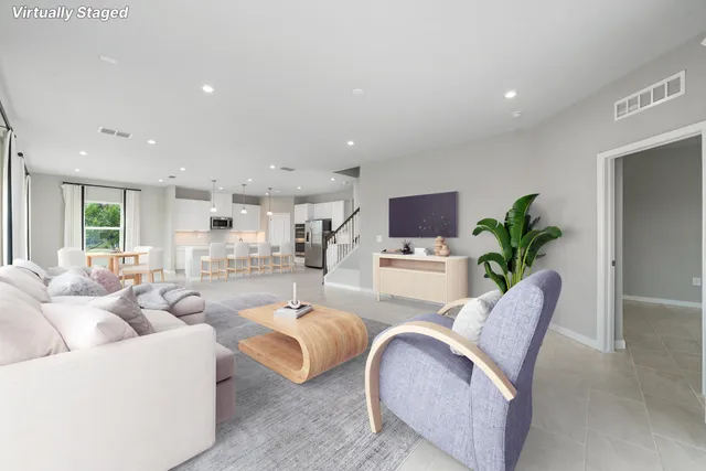 a living room with furniture white walls and a dining table with kitchen view