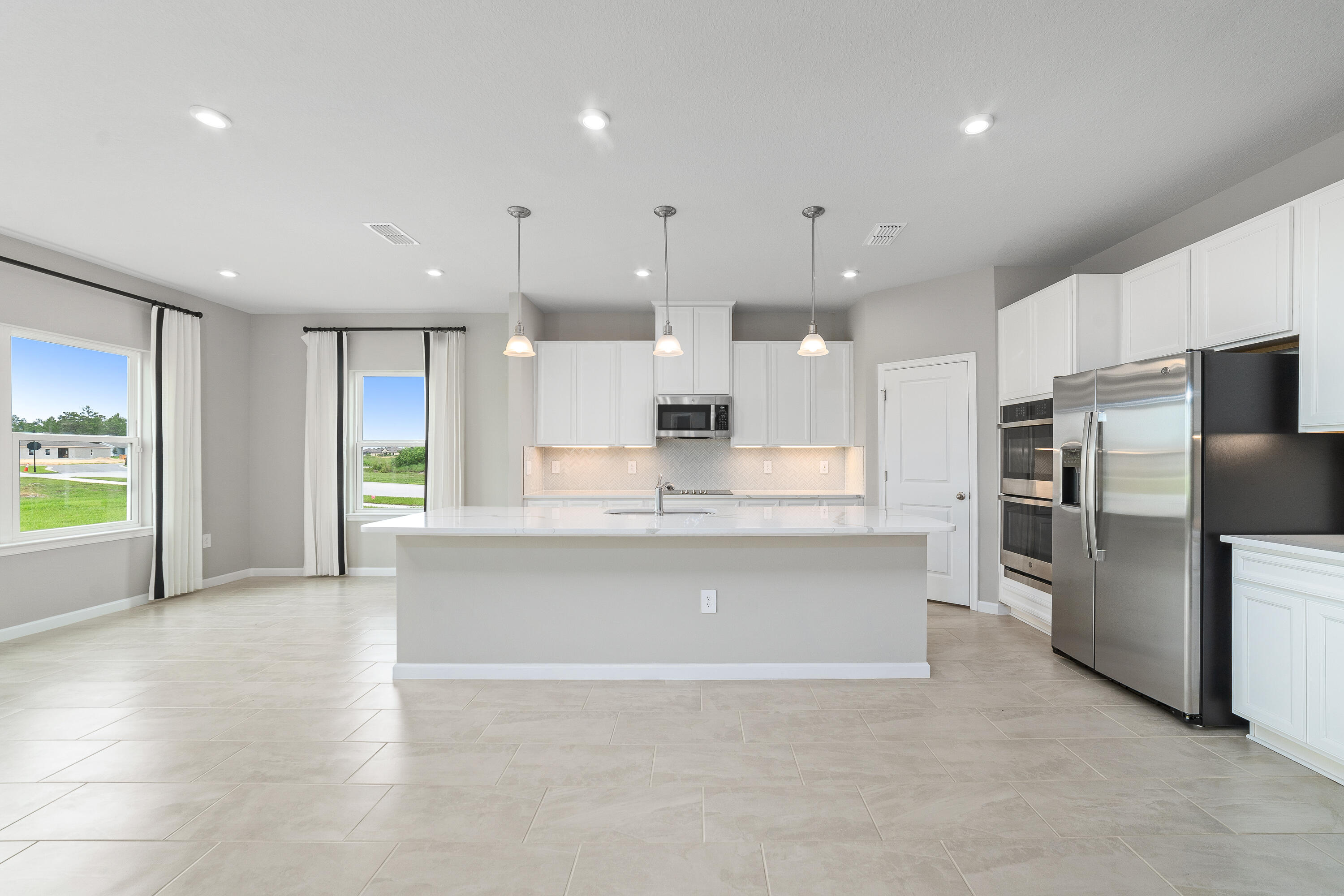 6555 Pomello Court Vero Beach, FL 32967 - Photo 9 of 35 a large kitchen with stainless steel appliances kitchen island granite countertop a large counter top stainless steel appliances and cabinets