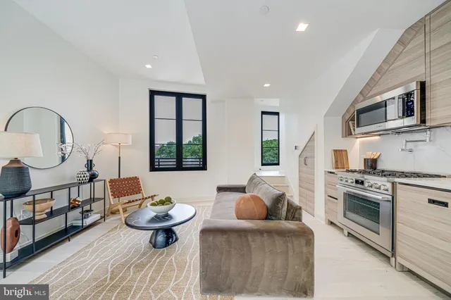 a kitchen with stainless steel appliances a stove a sink dishwasher a microwave oven and a dining table with wooden floor