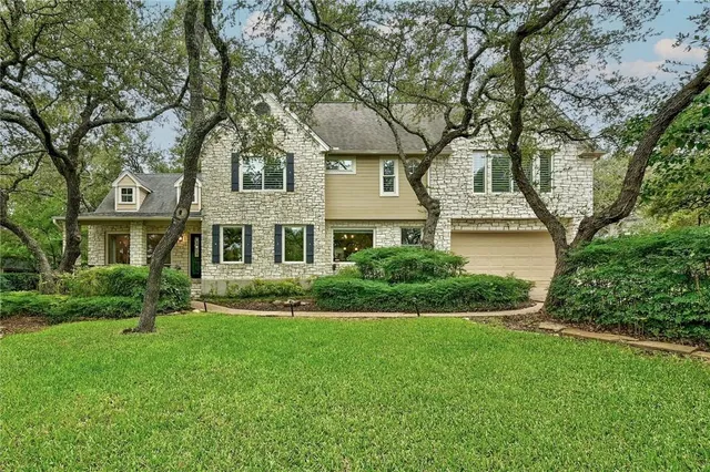 a front view of a house with a yard and trees