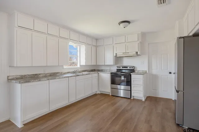 a kitchen with granite countertop a refrigerator and a stove top oven