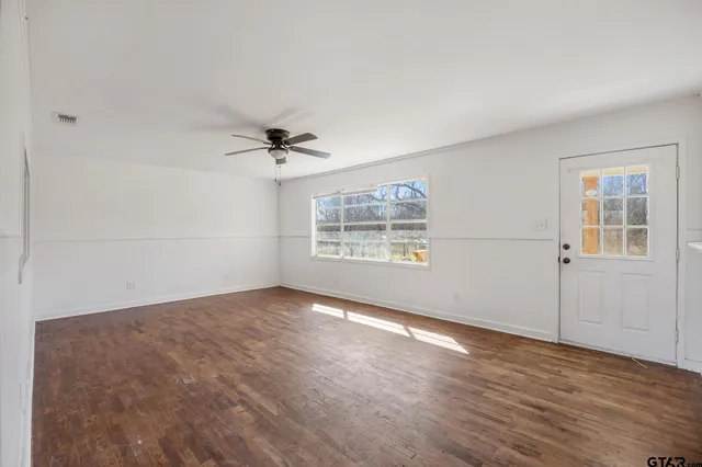 a view of empty room with wooden floor and fan