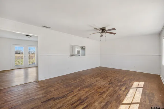a view of an empty room with wooden floor and windows