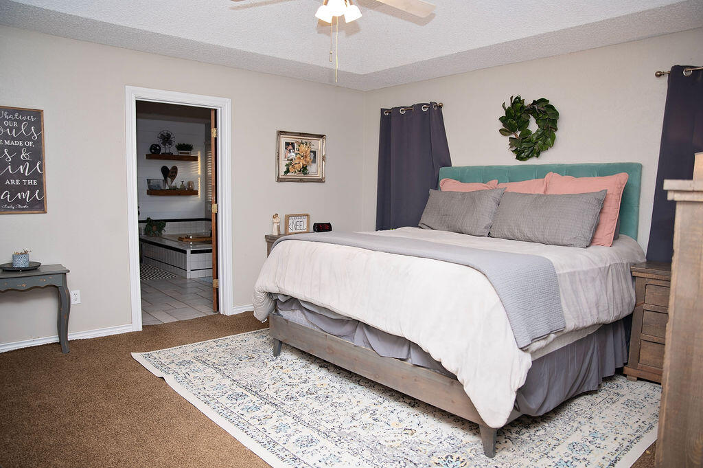 2917 Quail Ridge Road Denver City, TX 79323 - Photo 14 of 55 a spacious bedroom with a bed a dresser and book shelf