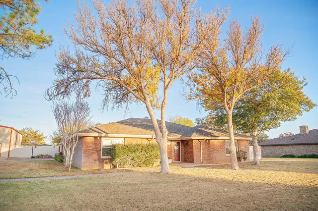 a backyard of a house with large trees and plants